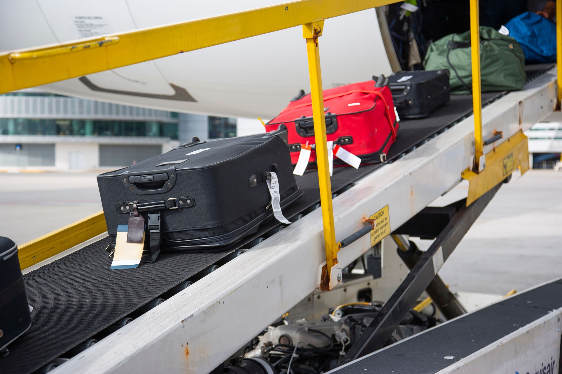 Luggage on conveyor belt being loaded onto an airplane at the airport.