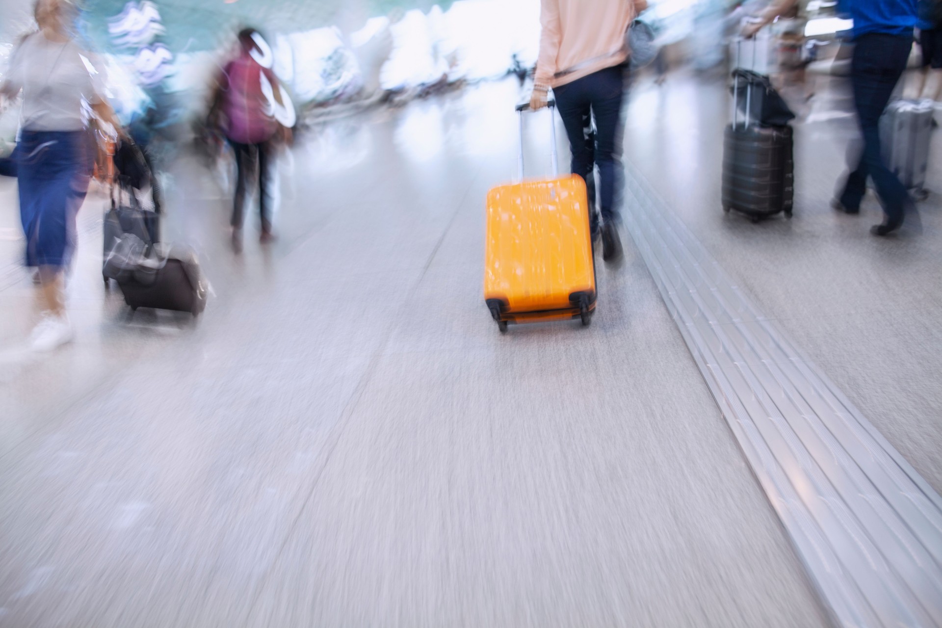 Passenger in a hurry to get to flight with rolling luggage in airport terminal